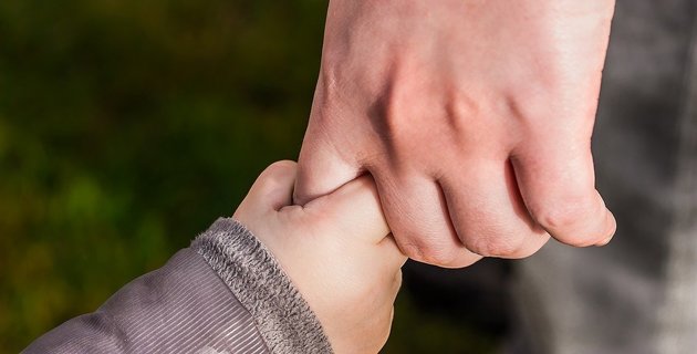 Häusliche Gewalt: Eine Frauenhand hält eine Kinderhand.