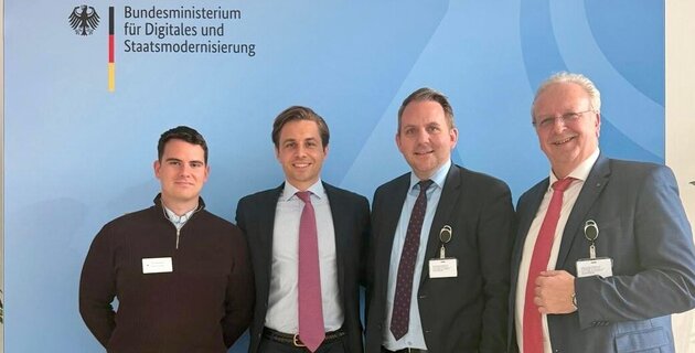 vier Männer stehen vor einer blauen Leinwand