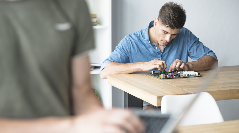 Ein junger Mann sitzt am Tisch und arbeitet an einer Festplatte