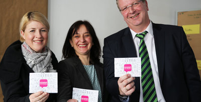 Zwei Frauen und ein Mann mit dem Buch „ICOON for refugees“ 