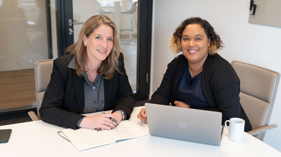 Soziale Wohnraumagentur Köln Winkler und Shumpert Ina Winkler und Sheba Shumpert sitzen zusammen am Tisch