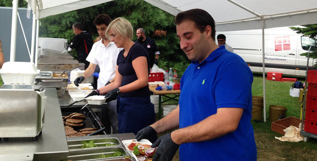 Mitarbeiter der Auxilio stehen beim Jubiläumsfest am Grill.