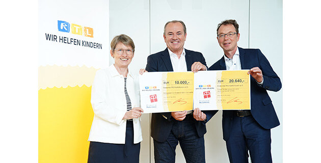Spende RTL-Stiftung 2022 – Scheckübergabe Eine Frau und zwei Männer halten zwei symbolische Spendenschecks in den Händen.