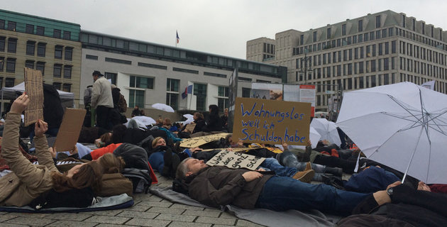 Mehrere Menschen liegen als Zeichen gegen Wohnungsnot auf dem Boden