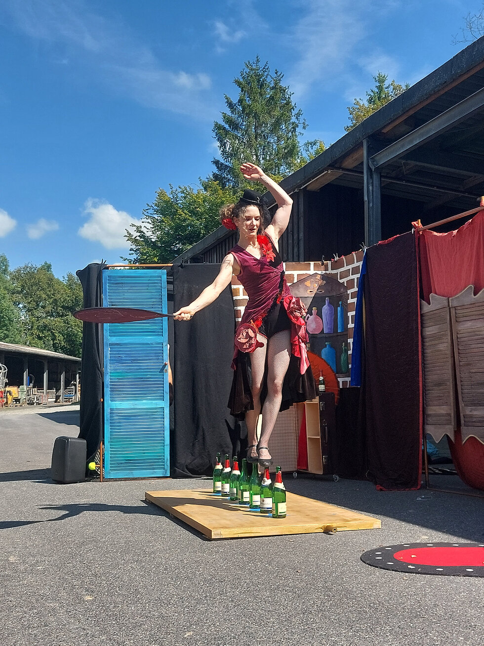 Wohnhilfen Oberberg Valerie Patisserie Eine Frau balanciert auf Flaschen.