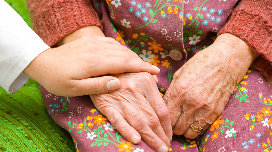 Eine Betreuerin hält die Hand einer Besucherin der Tagespflege