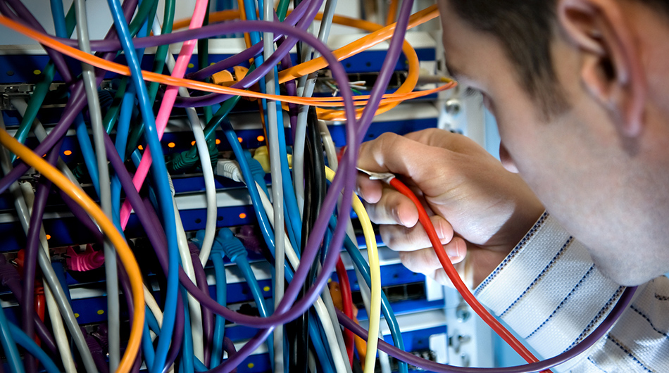 Umschulung Fachinformatiker auf Bildungsgutschein Fachinformatiker für Systemintegration vor einem großen Kasten mit Kabeln