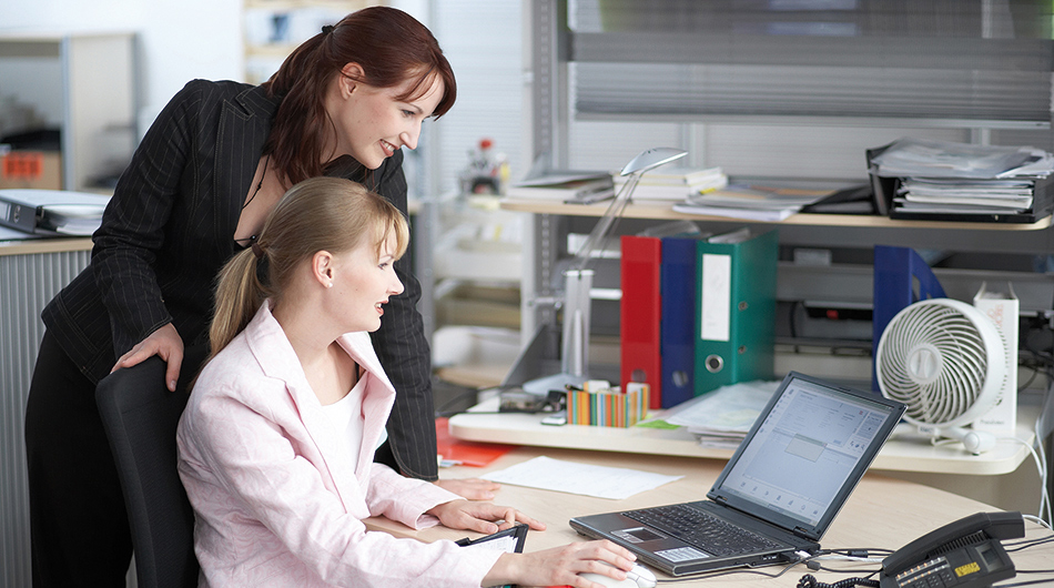 2 Frauen in der Umschulung für Kaufleute für Büromanagement vor einem PC