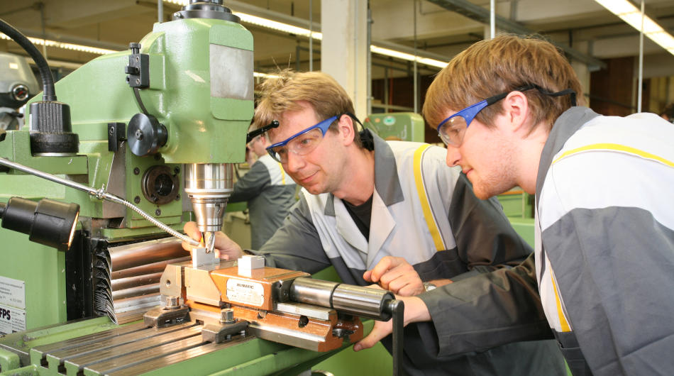 Umschulung mit Bildungsgutschein Fachkraft für Metalltechnik: Zwei Männer an einer Fräsemaschine.