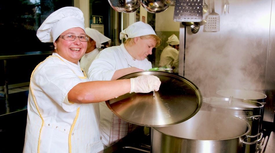 Projekt Opti:Mahl: Zwei Frauen hantieren mit Töpfen in einer Großküche.