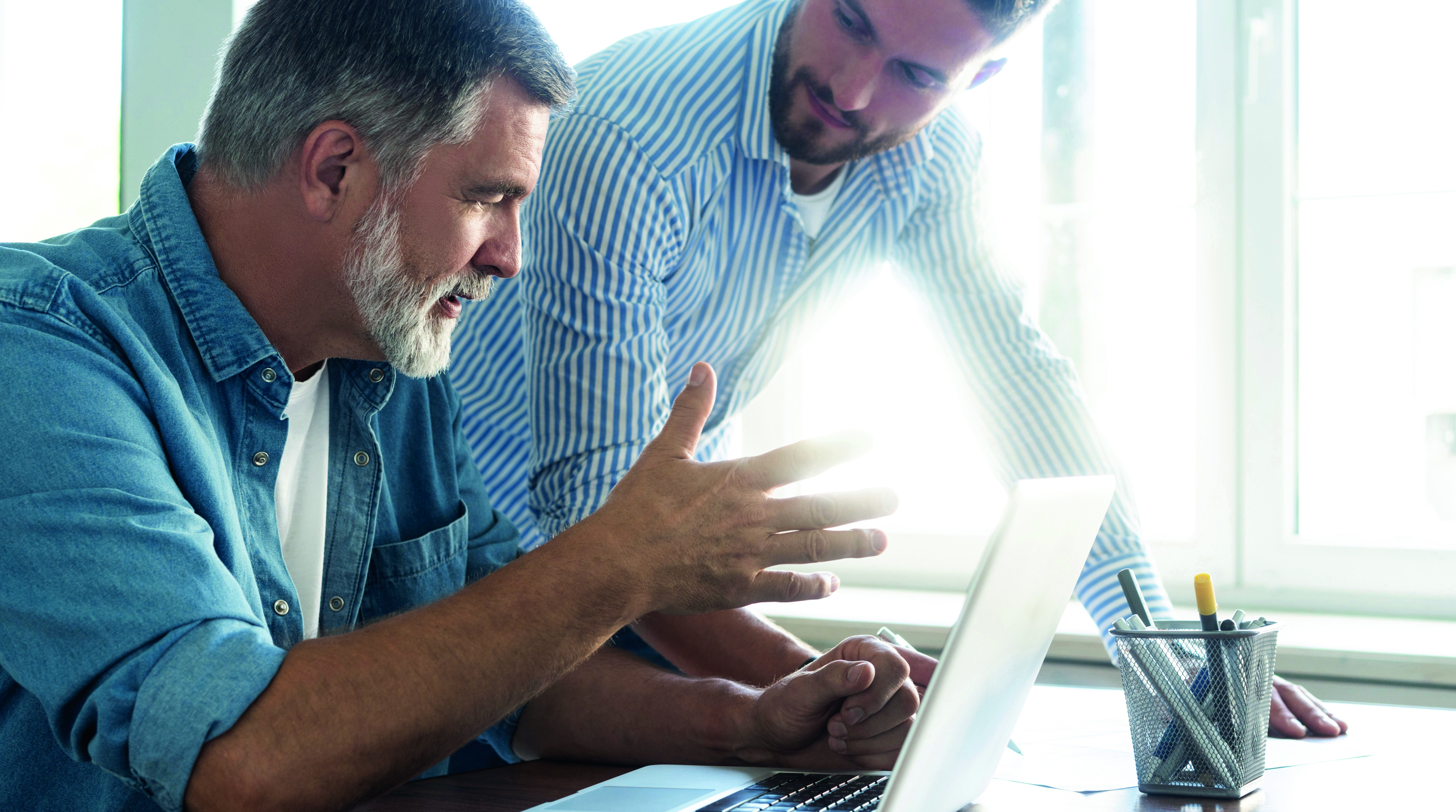Zwei Männer sitzen vor dem Laptop und unterhalten sich