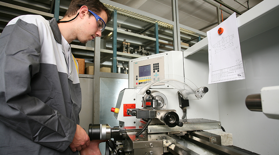 Fachpraktiker für Metalltechnik vor verschiedenen Geräten.