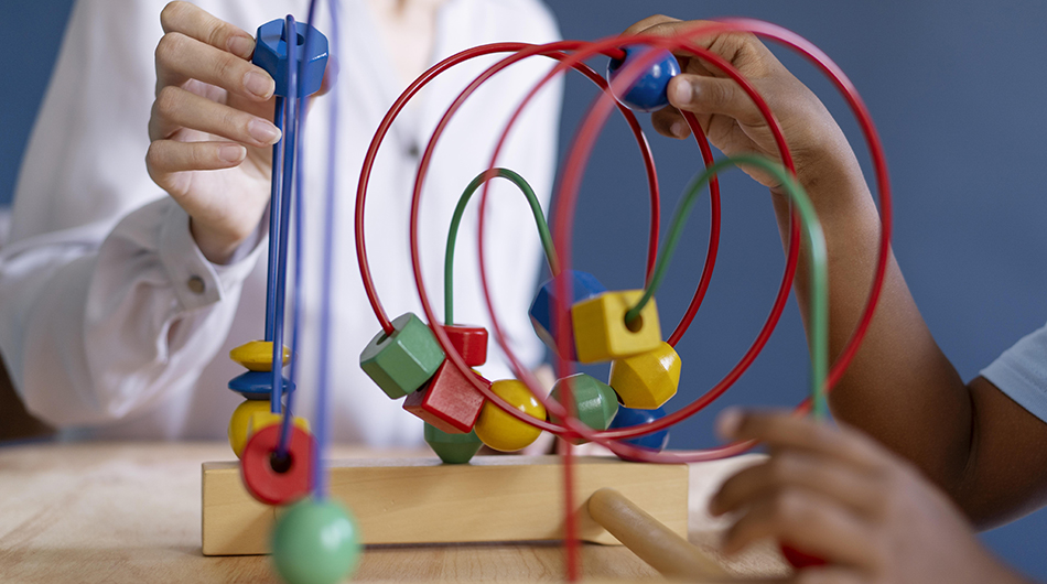 Kinder- und Jugendhilfe Therapie Eine Frau und ein Junge spielen mit einem Holzspielzeug