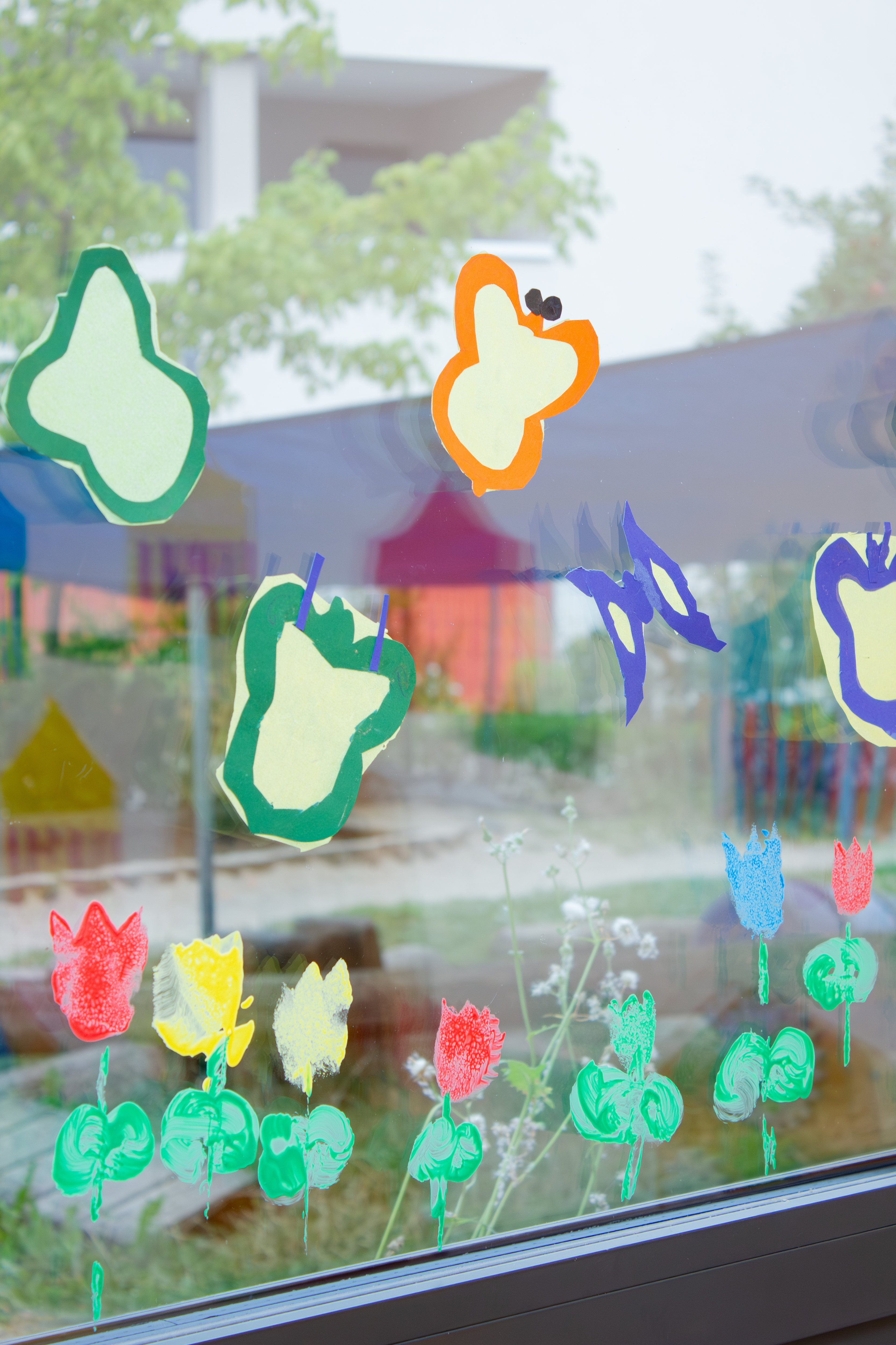 Bunte Schmetterling und Blumen auf einem Fenster der Kita Morgenland