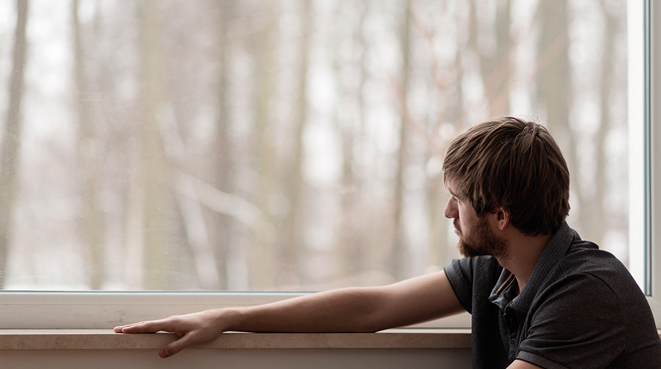 Junge mit Autismus guckt aus dem Fenster