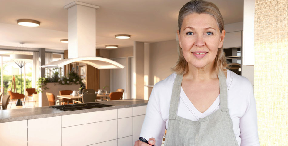 Eine Frau mit Schürze steht vor einer Kücheninsel.