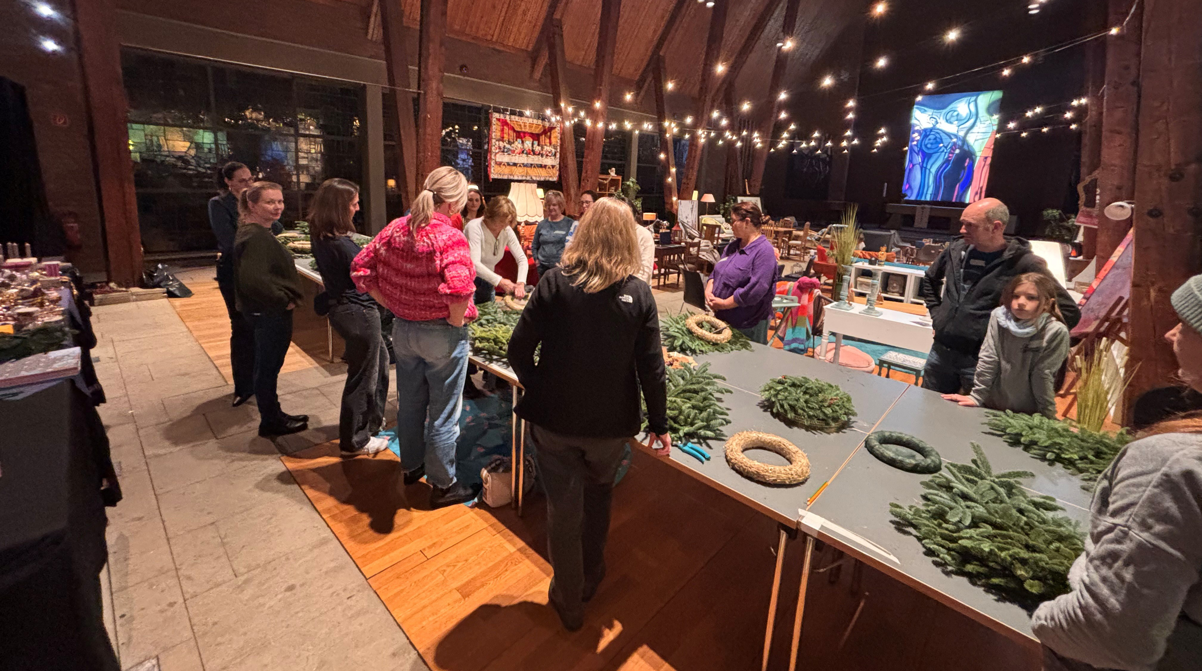 Kirche Adventskränze Mehrere Personen stehen am Tisch und basteln einen Adventskranz