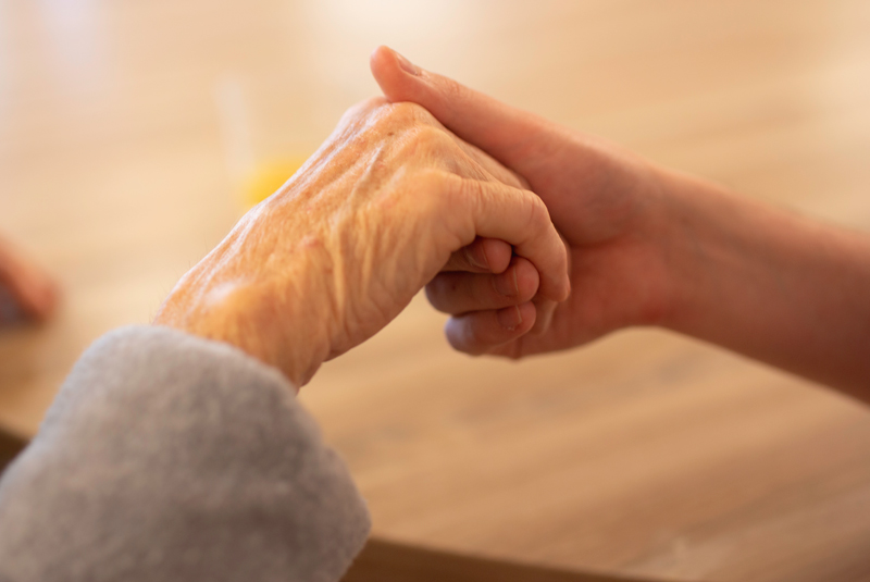 Zwei Hände Eine Hand mit vielen Falten wird von einer anderen Hand gehalten