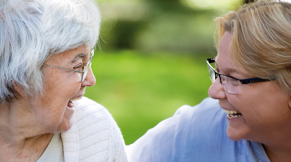 Ehrenamt in Köln: Eine Frau und eine Seniorin lachen gemeinsam.