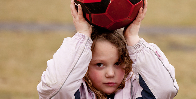ein Mädchen hält einen Ball über dem Kopf